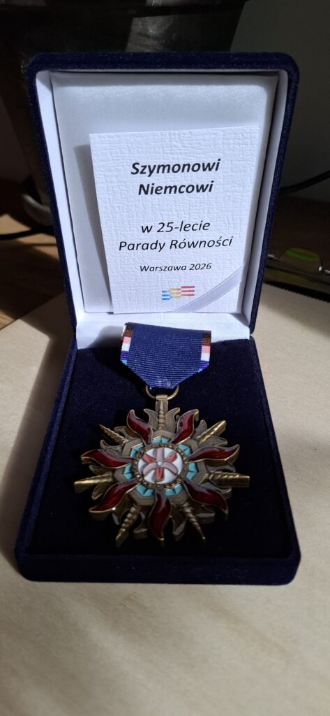 Order Równości przyznany Szymonowi Niemcowi z okazji 25-lecia Parady Równości w Warszawie, leżący w otwartym, granatowym etui